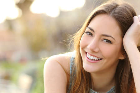 Woman smiling with perfect smile and white teeth in a park and looking at cameraの写真素材