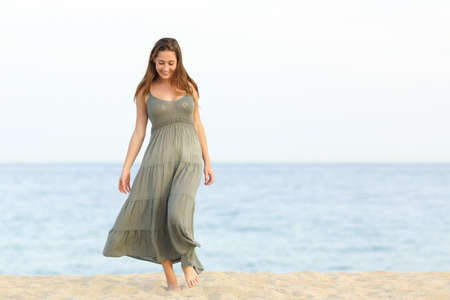 Candid feminine dreamer girl walking enjoying carefree on the sand of the beach towards cameraの写真素材