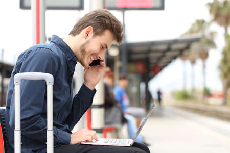 Freelancer working with a laptop and phone in a train station while is waiting for transport