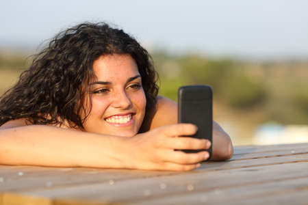 Funny girl watching social media in smart phone relaxing in a parkの写真素材