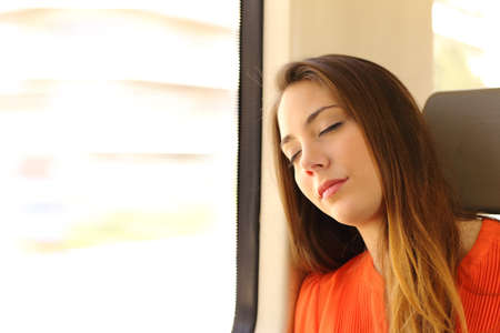 Passenger woman sitting and sleeping inside a train during a travelの写真素材