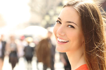 Woman face smile with perfect teeth and smooth skin looking you on the street