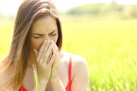 Woman with allergy coughing in a green color field in summerの写真素材