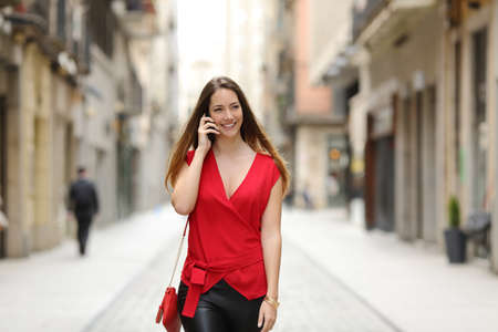Fashion and sexy woman walking and talking on the mobile phone in a city streetの写真素材