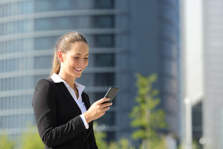 Executive working with a mobile phone in the street with office buildings in the backgroundの写真素材