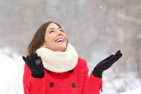 Candid happy girl enjoying snow in winter wearing a red jacketの写真素材
