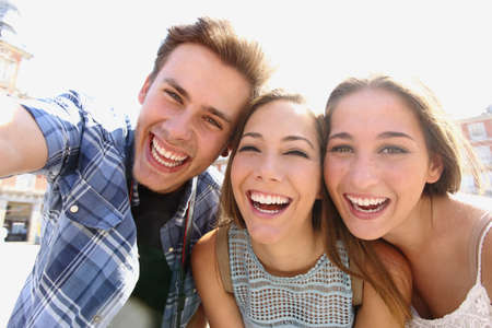 Group of happy teen friends laughing and taking a selfie in the street Group of happy teen friends laughing and taking a selfie in the street