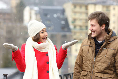 Happy couple enjoying snow in a snowy day in the street of a townの写真素材