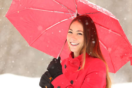 Beauty woman in red with an umbrella in a snowy winter