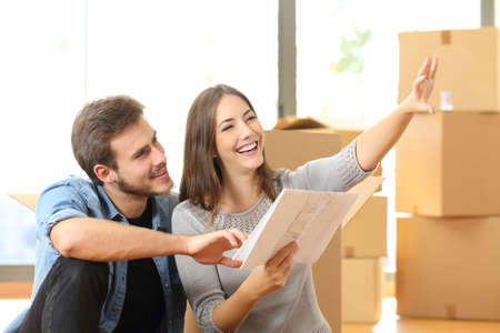 Happy couple planning decoration when moving home sitting on the floor
