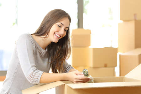 Woman packing or unpacking belongings in a carton box when moving home