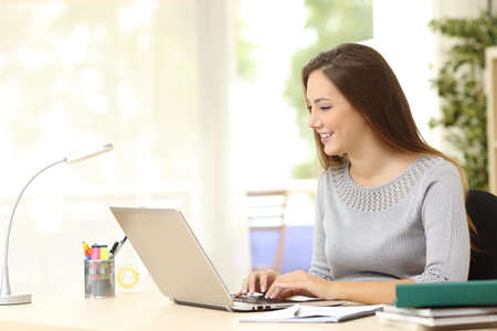 Woman working typing in a laptop on a desk at home