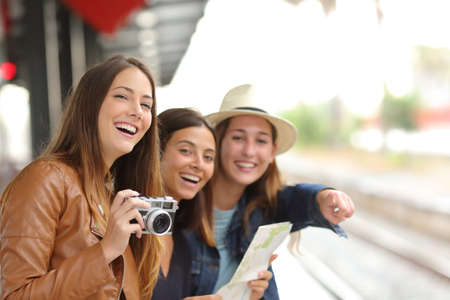 Group of three traveler girls traveling and waiting in a train station platformの写真素材
