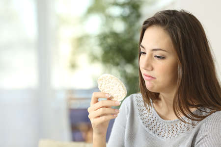 Girl disgusted looking a dietetic cookie. Bad diet conceptの写真素材