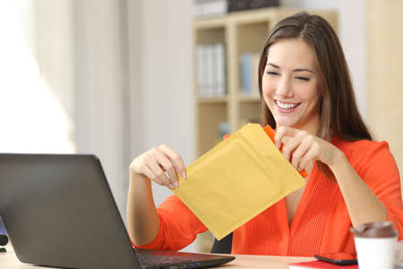 Freelancer opening a padded envelope in an office or homeの写真素材