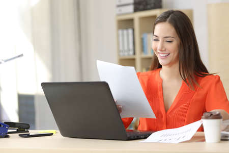 Entrepreneur on line working and comparing forecasting and graphic documents in a little office desktop or homeの写真素材