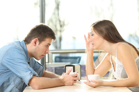 Dumbfounded man looking at beautiful bosom of an annoyed girl in a date in a coffee shopの写真素材
