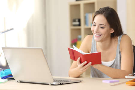 Happy student consulting schedule in a red agenda in a desk at home