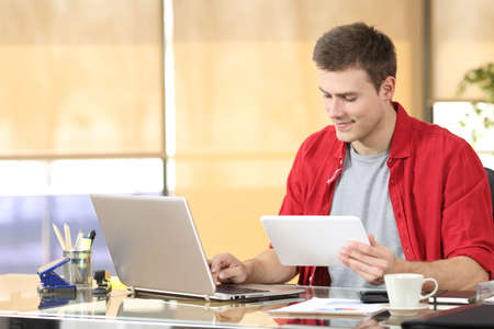 Portrait of a concentrated entrepreneur working on line with technology equipment sitting in a desktop at officeの写真素材
