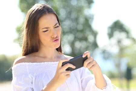 Amazed girl playing games on line with a smart phone in a parkの写真素材