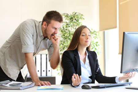 Angry businessman hating to his relaxed colleague at officeの写真素材