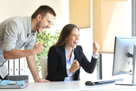 Excited businesspeople co-working watching a desktop computer on line