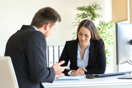 Bad businessman trying to convince to a suspicious client during a difficult negotiation in a desktop at officeの写真素材