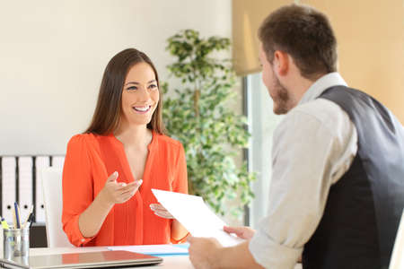 Confident woman and interviewer looking each other and talking during a job interview at office