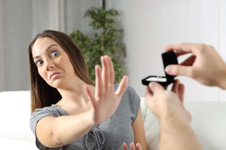 Scared girlfriend rejecting a marriage proposal at home. Humorous situationの写真素材