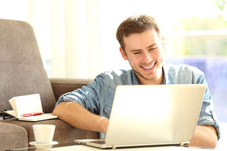 Front view of a man working with a laptop sitting on the floor of the living room at homeの写真素材
