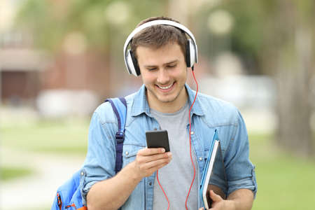 Front view of a student walking learning with audio lessons and walking towards cameraの写真素材