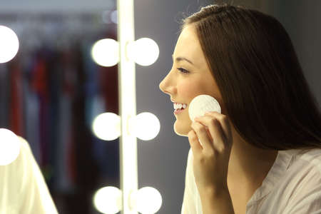 Side view of a woman removing make up with a remover in front of a mirrorの写真素材
