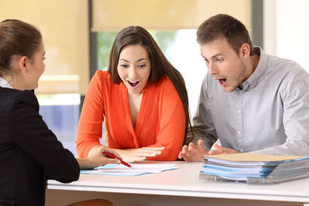 Two amazed customers reading contract conditions at officeの写真素材