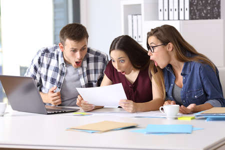 Three amazed employees reading a paper document at office