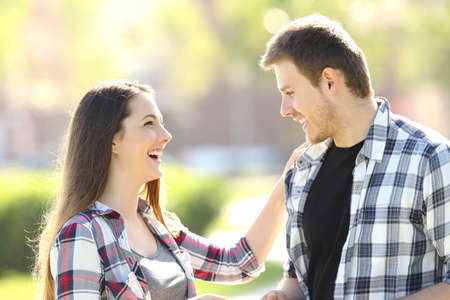 Side view of two friends flirting and talking affectionate in the streetの写真素材