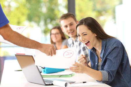 Excited student receiving an approved exam from the teacher in a classroom