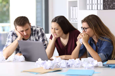 Three frustrated entrepreneurs trying to do a difficult job on line at officeの写真素材