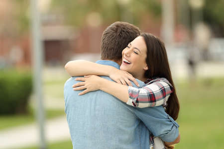 Happy encounter of two friends hugging outdoors in a parkの写真素材