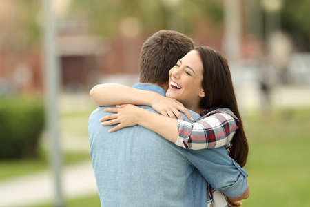 Happy encounter of two friends hugging outdoors in a park