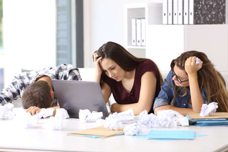 Three frustrated entrepreneurs with no ideas surrendering at office