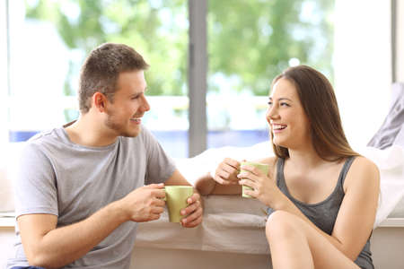 Happy couple talking and having breakfast in an hotel room or home with a green background outdoorsの写真素材