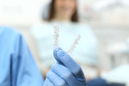 Dentist hand with gloves holding a silicone trainer in a consultation with a patient in the...
