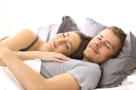 Happy couple sleeping together lying on a bed of an hotel room or homeの写真素材