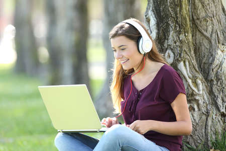Single teen listening and watching media content on line with headphones and a laptopの写真素材