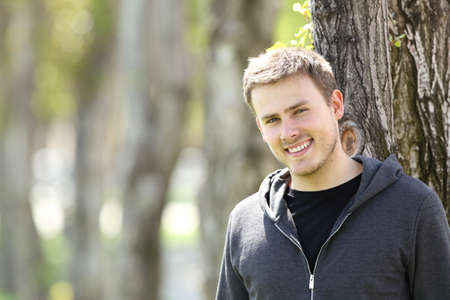 Portrait of a handsome teenager boy posing looking at you outdoors in a parkの写真素材
