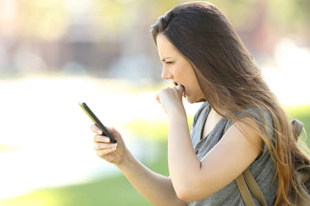 Side view of a girl angry with her mobile phone in the streetの写真素材