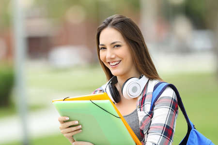 Student standing and posing looking at you holding folders in the streetの写真素材