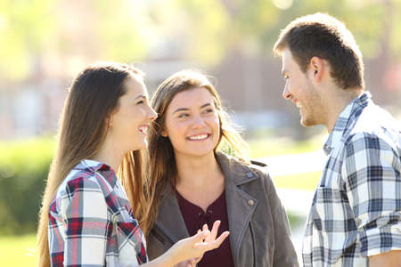 Three happy friends talking and laughing standing together in the streetの写真素材