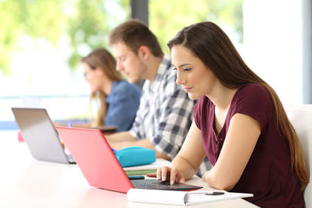 Three concentrated students studying on line in a classroomの写真素材
