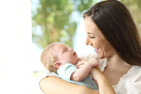 Mother holding and playing with her baby at homeの写真素材